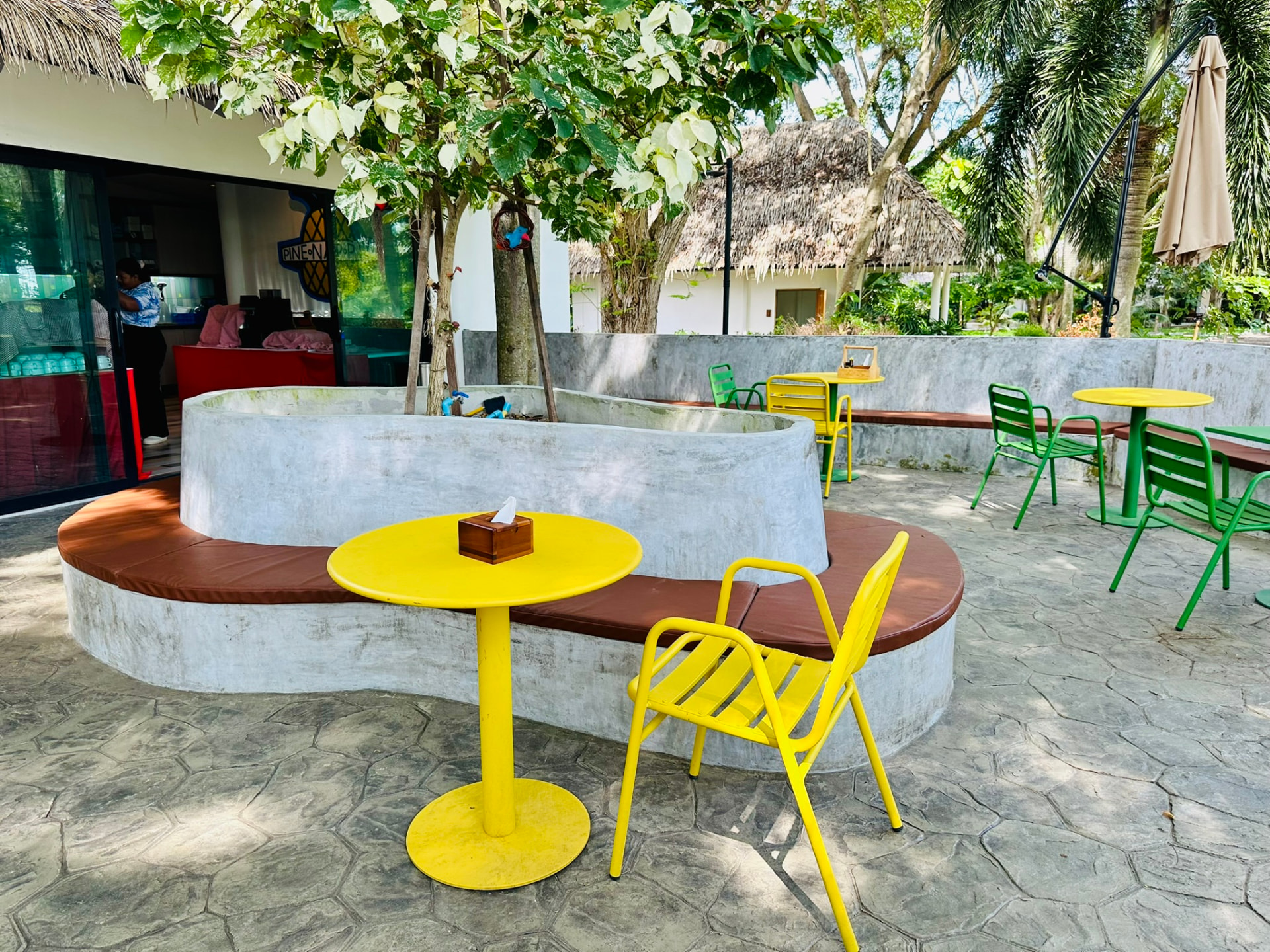 The PineNapple Cafe counter with staff inside and a curved planter bench outside