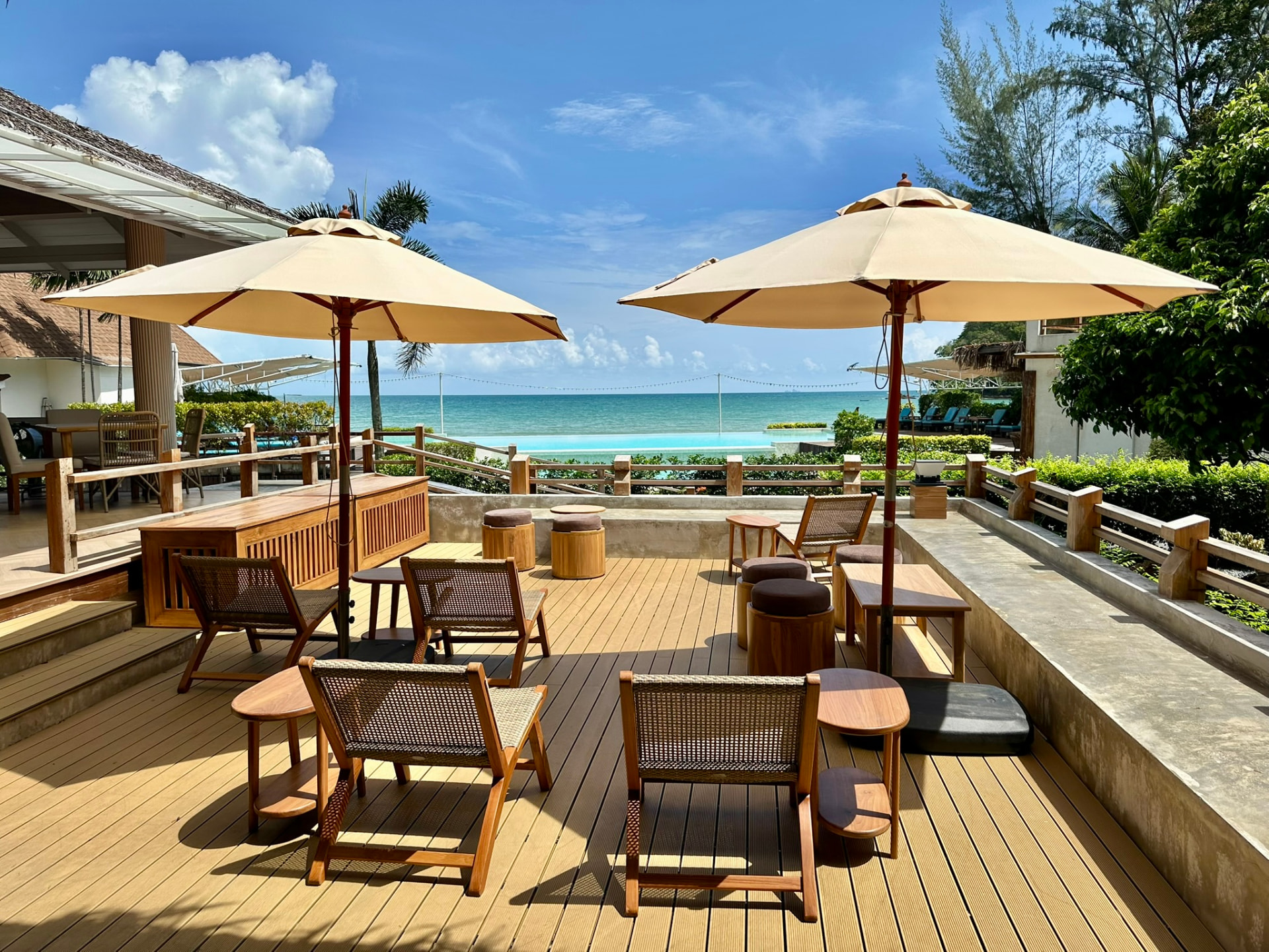 Umbrellas, teak loungers and low tables on the deck above the pool at Breezy Bites