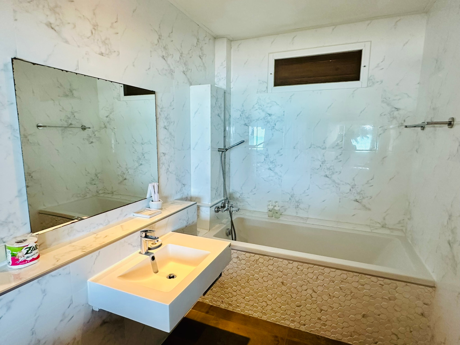 Marble bathroom with a bathtub, floating basin and wide mirror