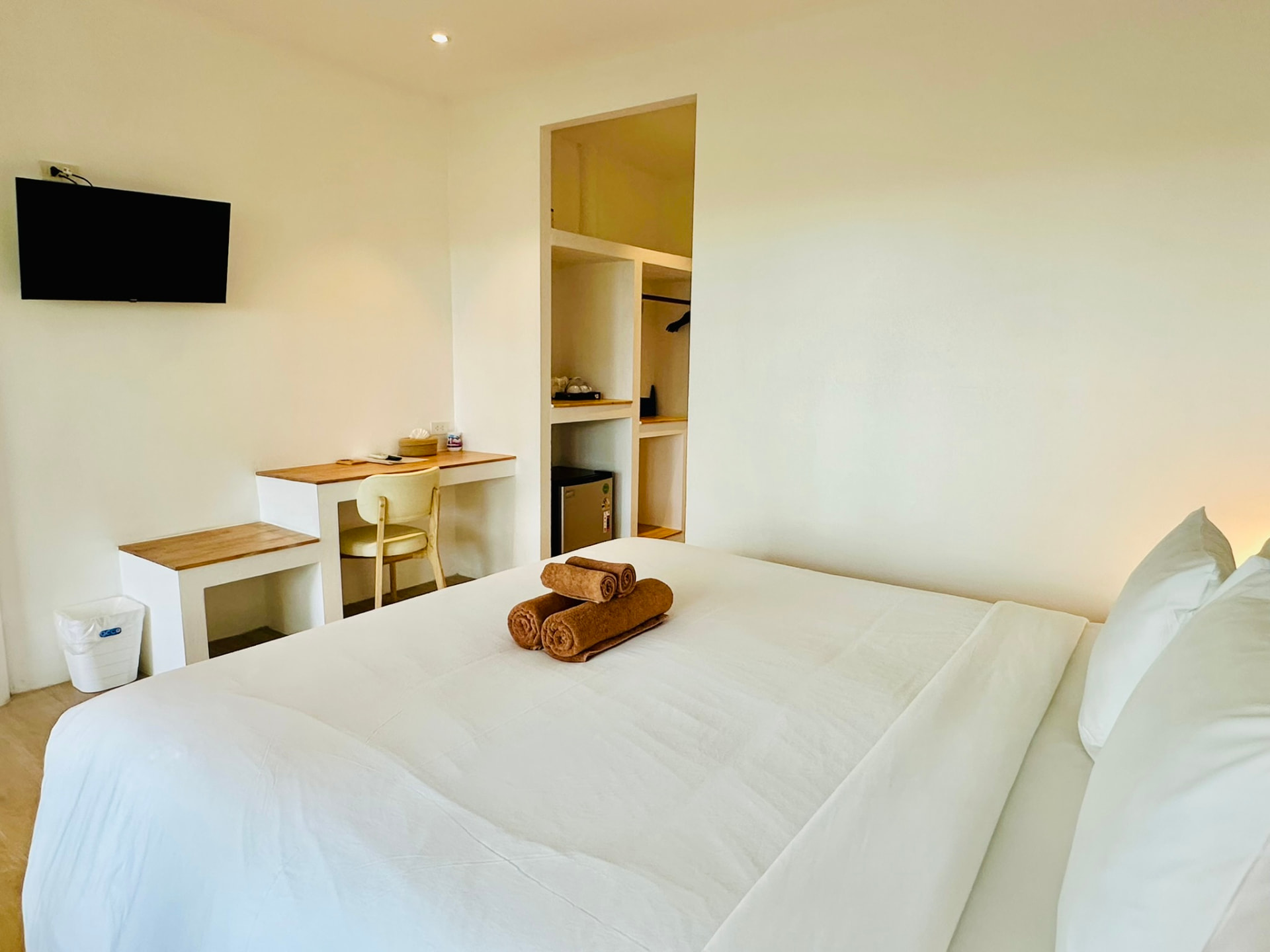 Bedroom with wall-mounted television, wooden desk and open dressing nook