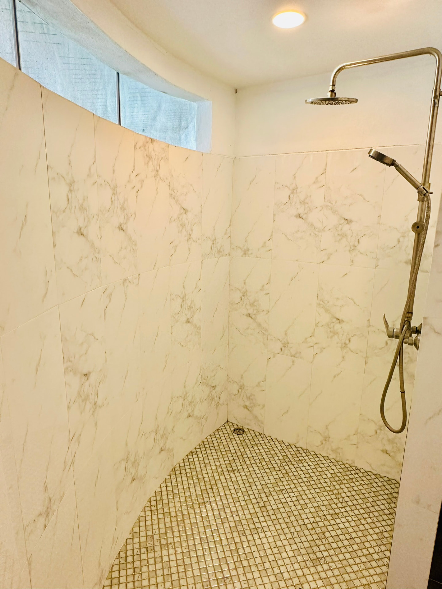 Walk-in rain shower with marble walls and mosaic tiled floor