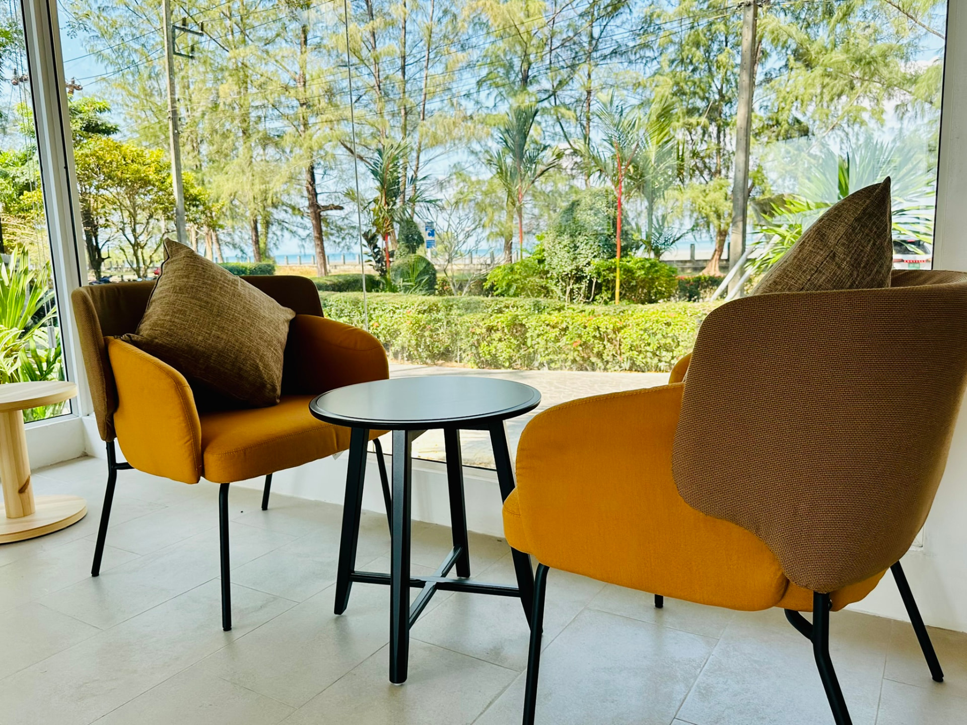 Two mustard armchairs and a small table by the window looking into the garden