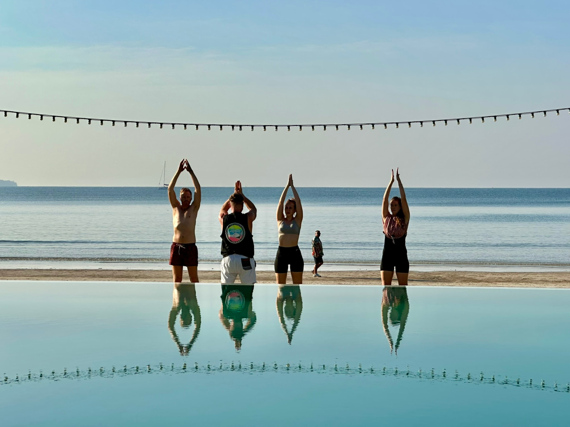 Four guests stretching, mirrored in the still infinity pool