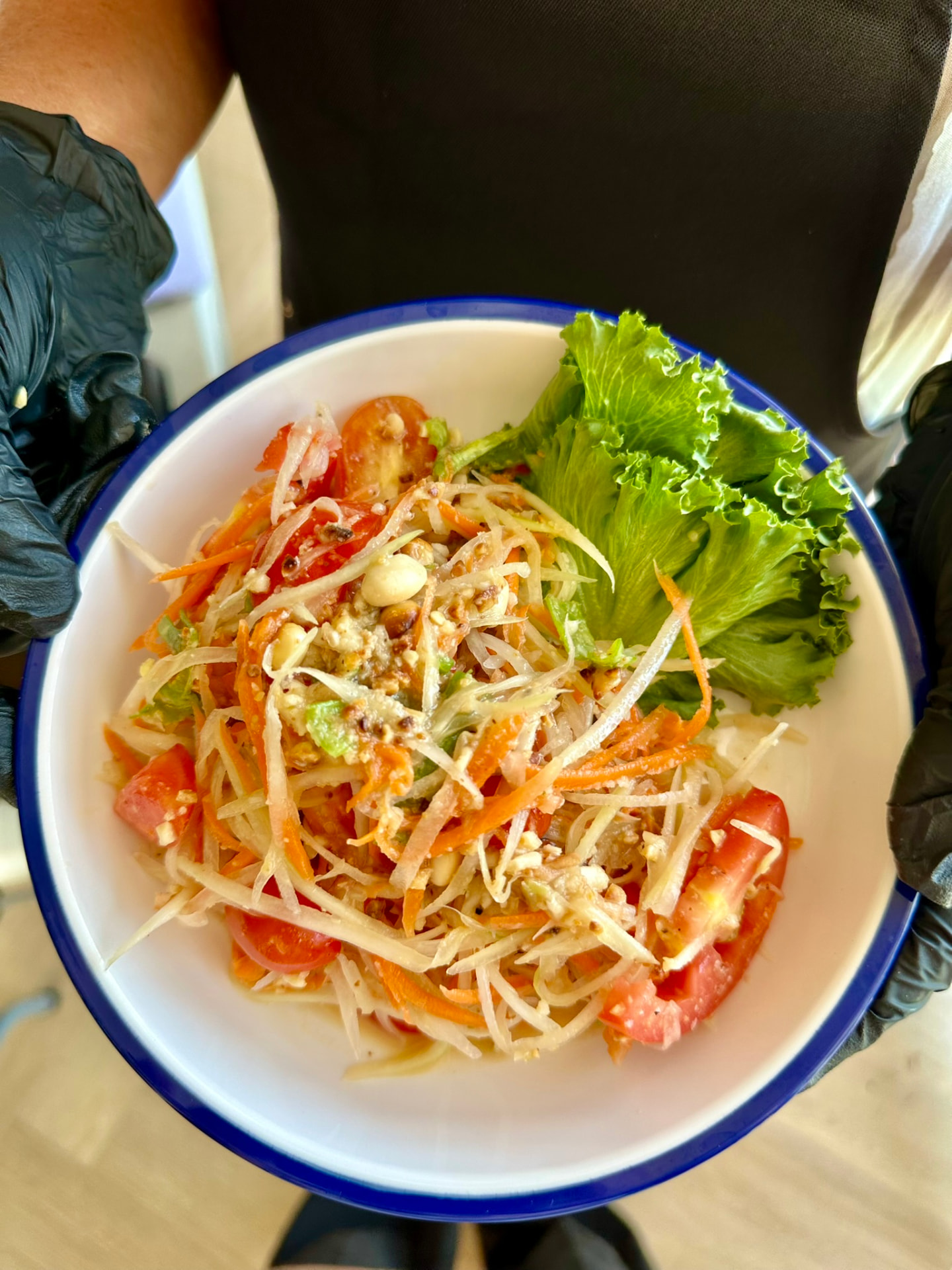 A finished plate of green papaya salad held by the chef