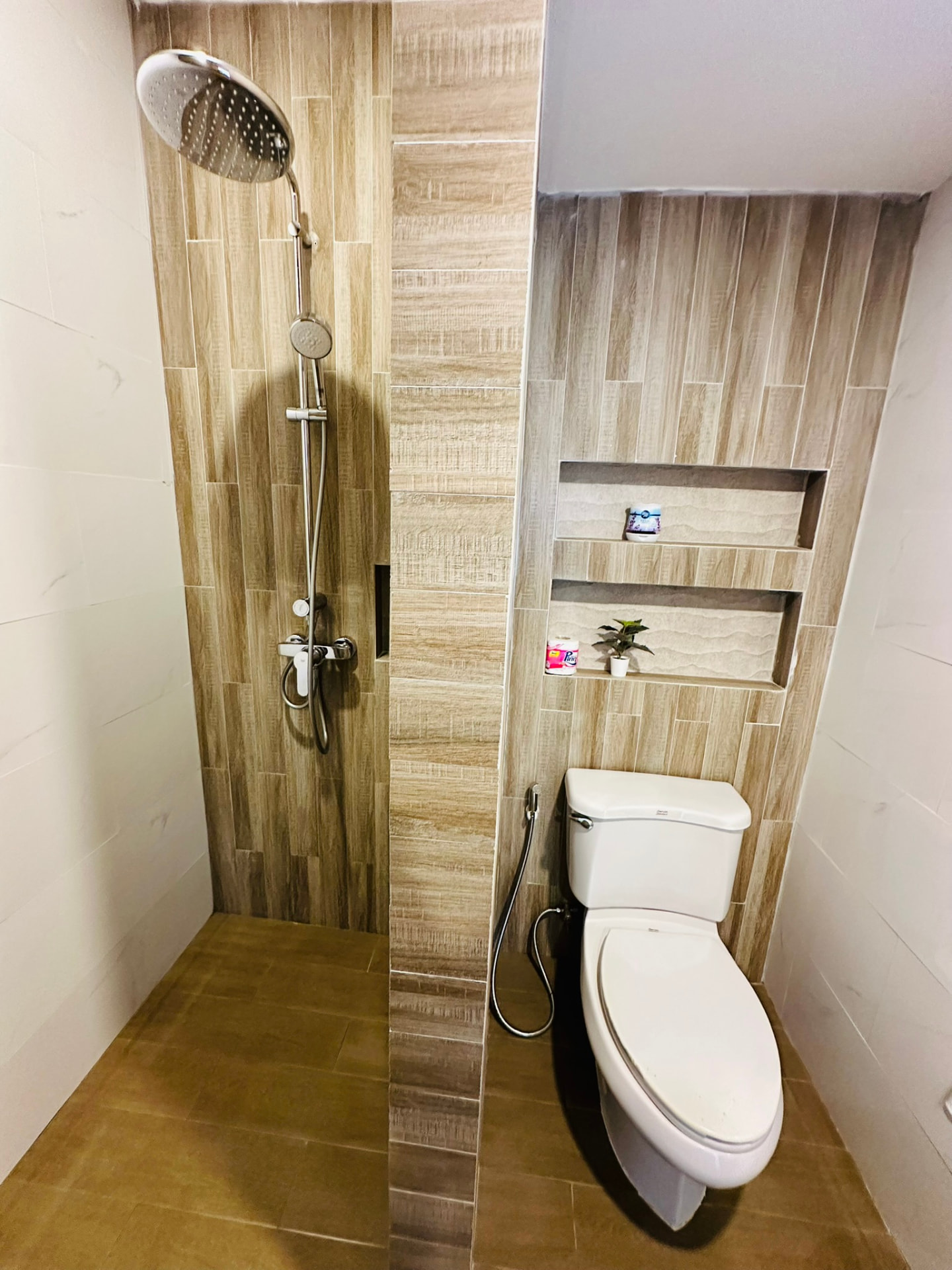 Walk-in rain shower and toilet with warm wood-effect tiling