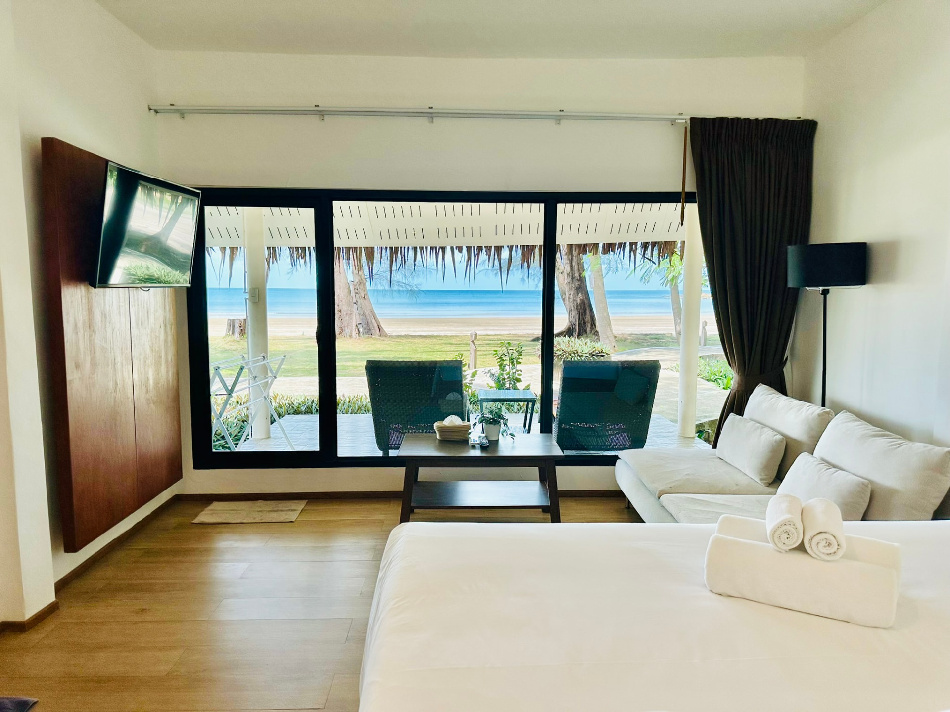 Beachfront bungalow interior with king bed, sofa and sliding doors opening to the sea