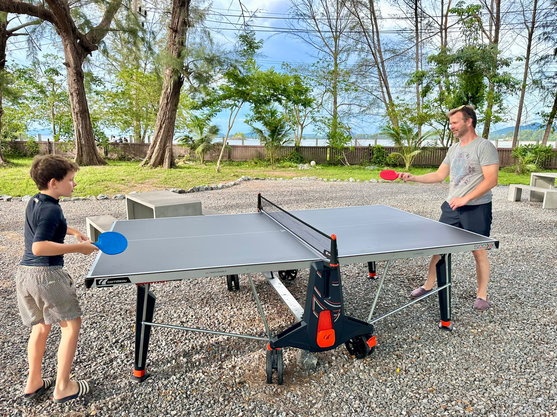 A guest serving across the table tennis table beside the beach