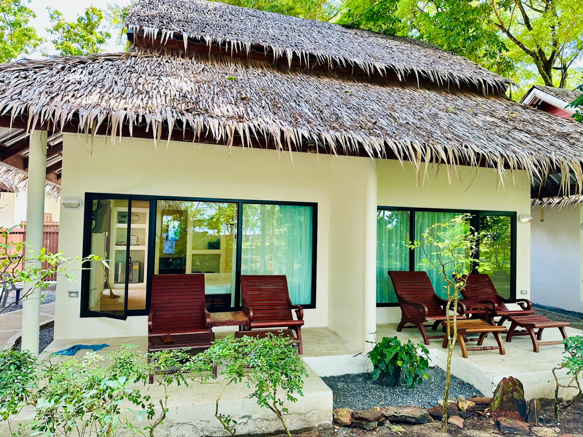 Thatched-roof bungalow with wooden loungers on the terrace, set in the garden