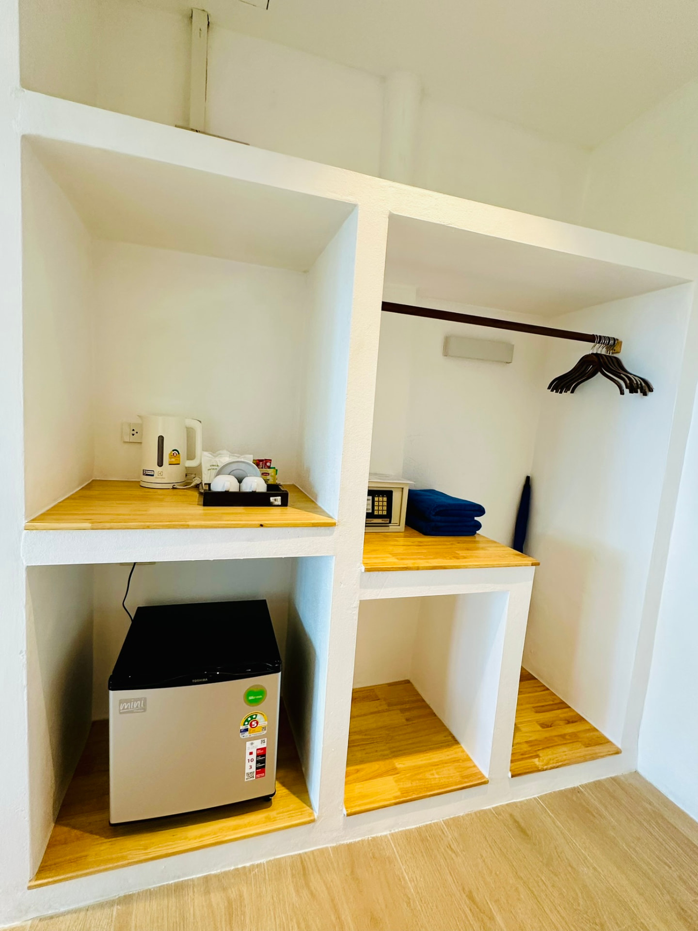 Open wardrobe with hangers, safe, kettle and mini fridge