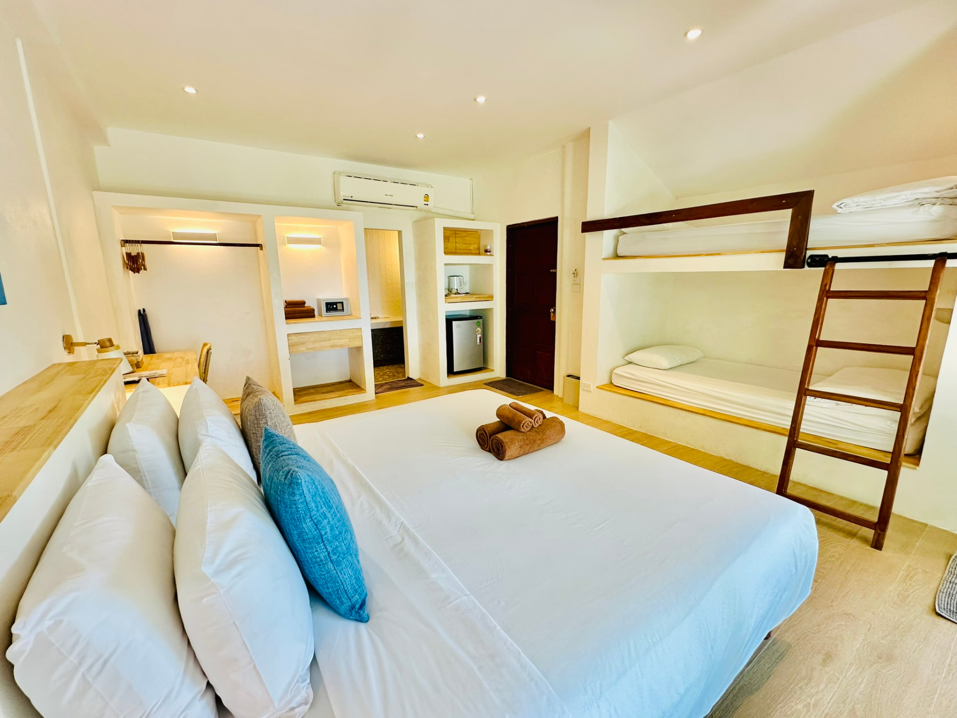 Bunk beds built into the wall beside the king bed with a wooden ladder