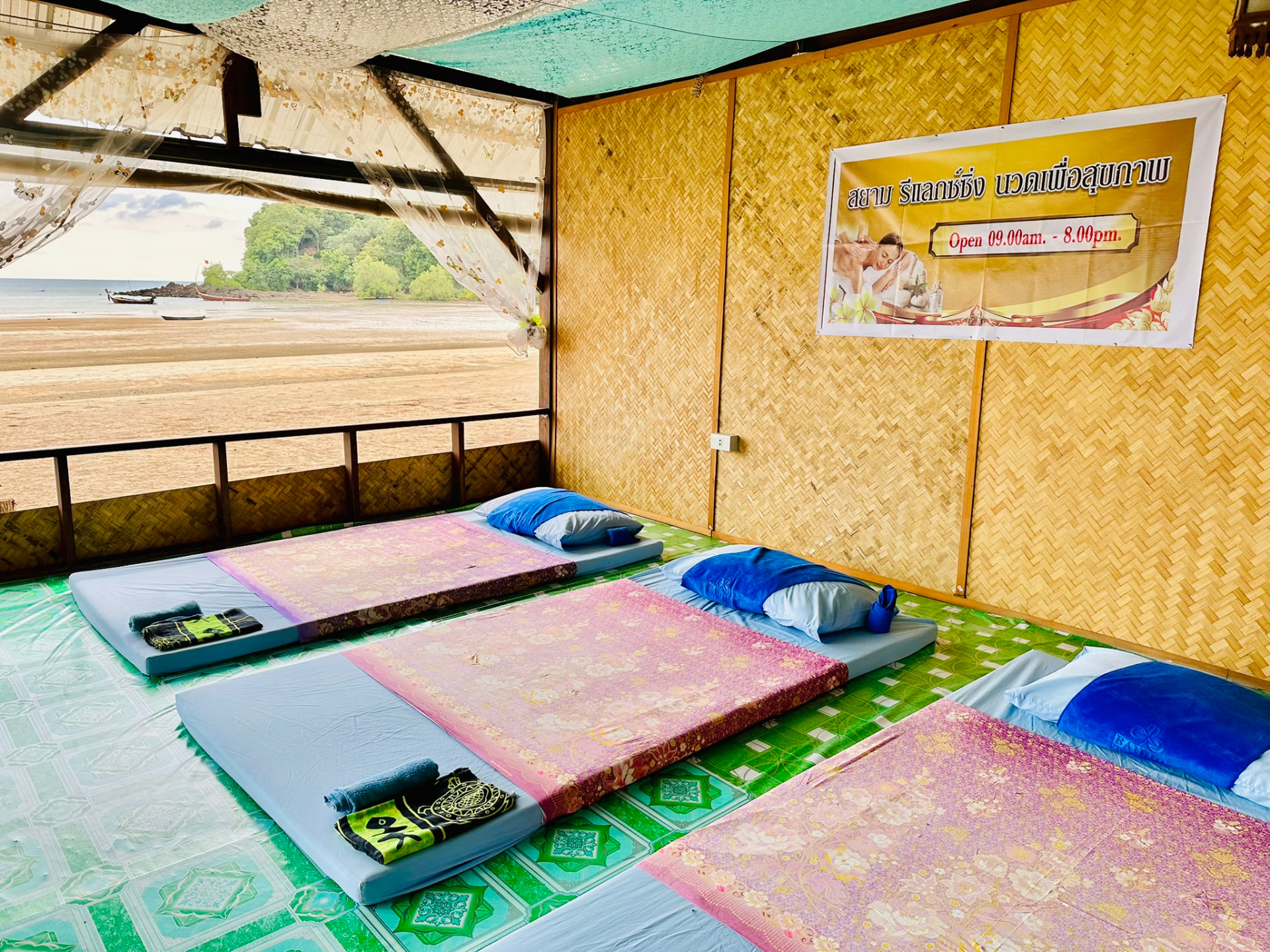 Woven bamboo walls and three massage mattresses with the beach through the opening