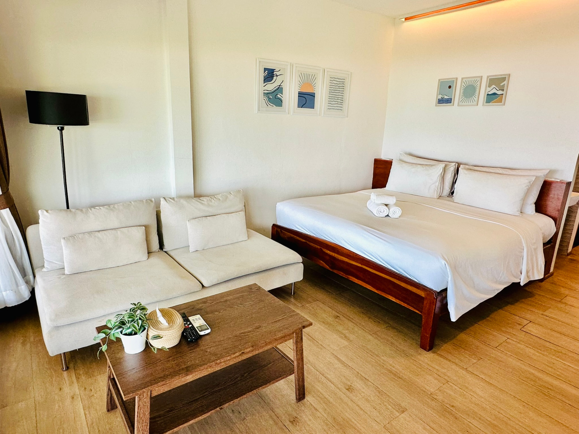 King bed and long sofa with framed coastal prints on the wall