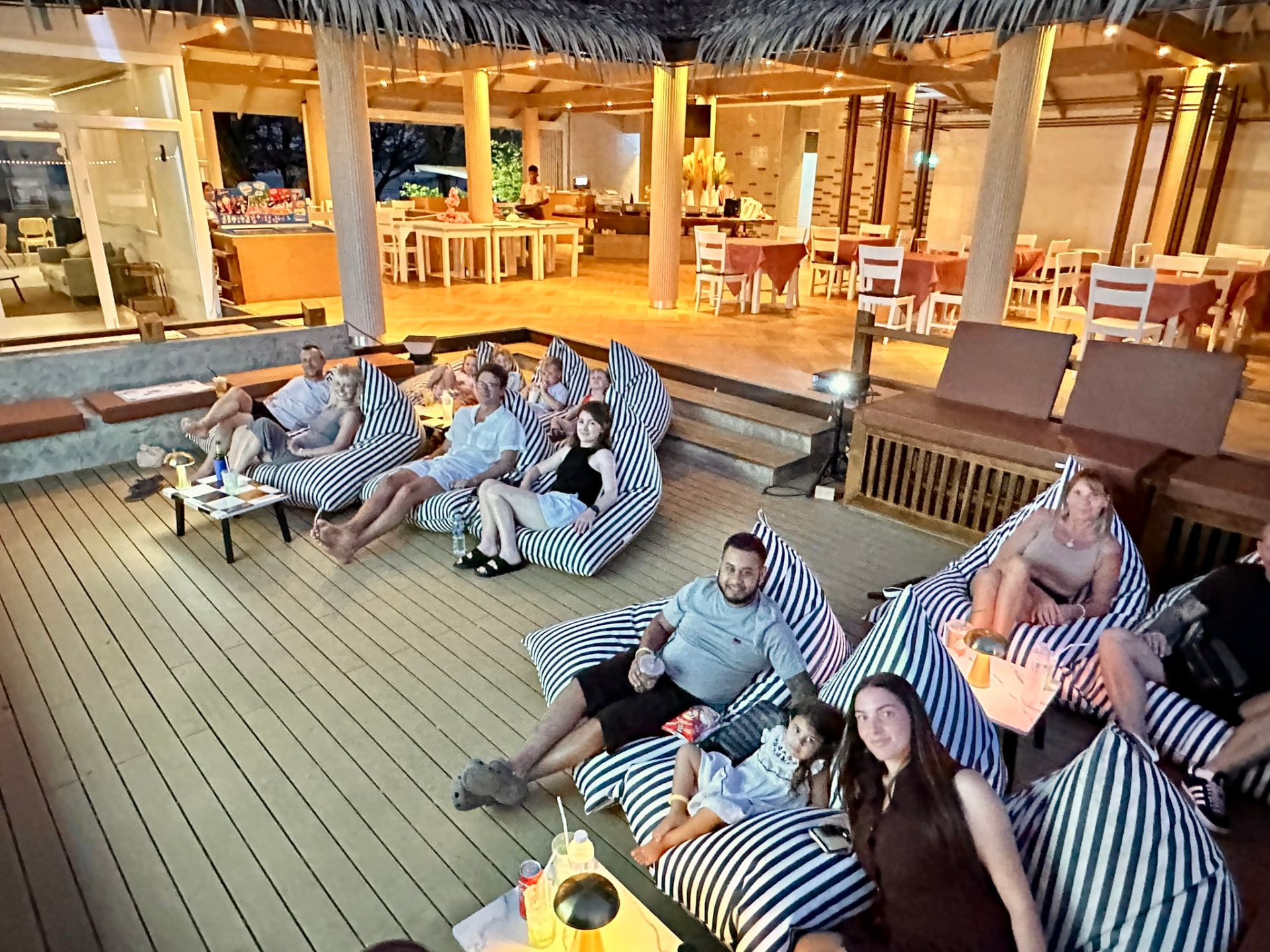 Parents and children smiling from bean bags at Breezy Bites during movie night
